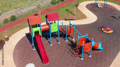 Empty playhouse and slide in a playground for kids. Deserted kindergarten park in residential neighborhood of a city during lockdown. Aerial view of colorful plastic equipment made for children play.