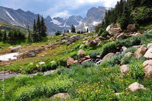 spectacular navajo, arapahoe, and shoshone peaks and a lovely mountain stream as seen in summer on the hiking trail up to isabelle lake in the indian peaks wilderness area, near nederland, colorado