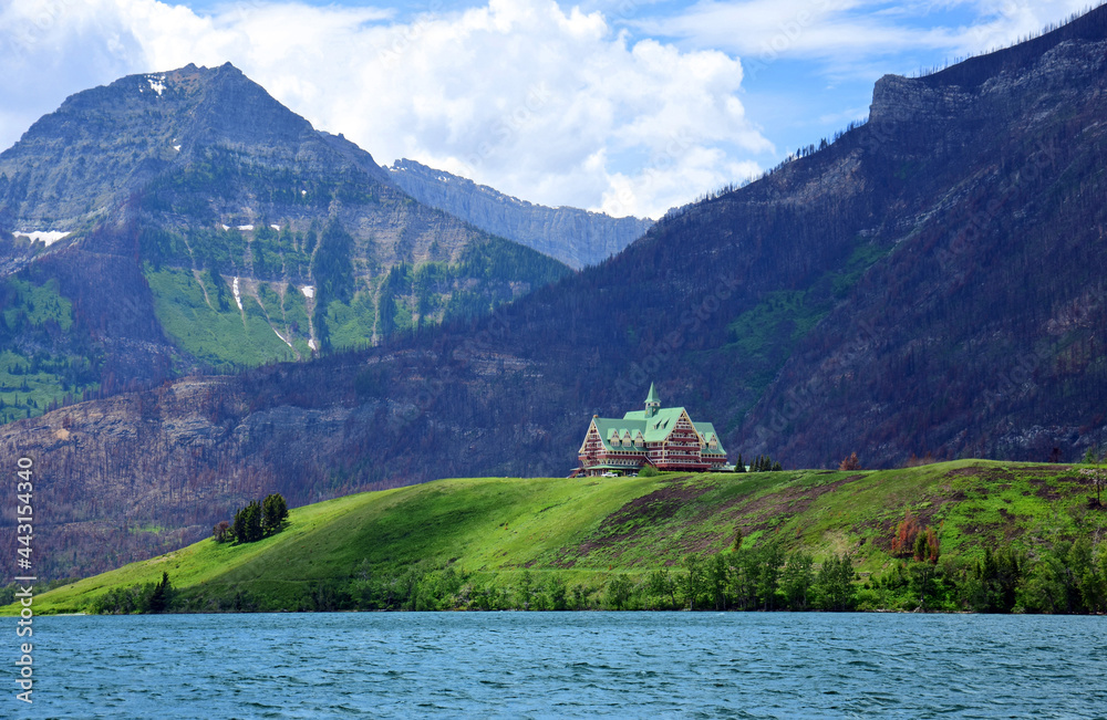 spectacular view  of the iconic prince of wales hotel and the canadian rocky mountains  across the turquoise-colored waterton lakes in summer, in waterton, alberta,  canada