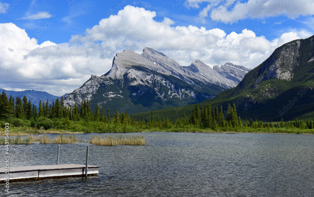 picturesque mount rundle and a boat pier on a sunny day, as seen across the vermilion lakes in banff national park, alberta, canada, in the canadian rockies
