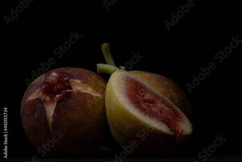 Photo of figs on a wooden board with a black background.