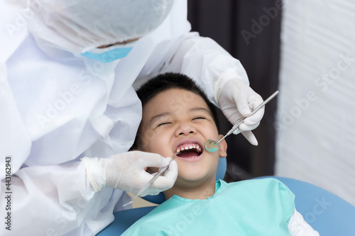 Dentist examining Asian little boy teeth in clinic.