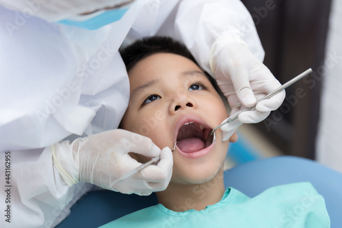 Dentist examining Asian little boy teeth in clinic.