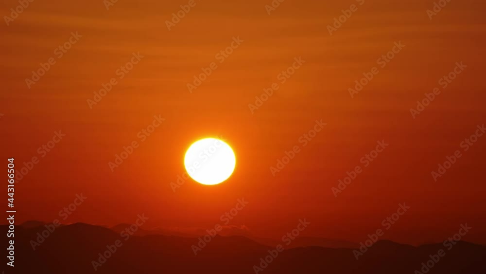 Time-lapse of sunset, orange sky in background Time-lapse of sunset, orange sky in background