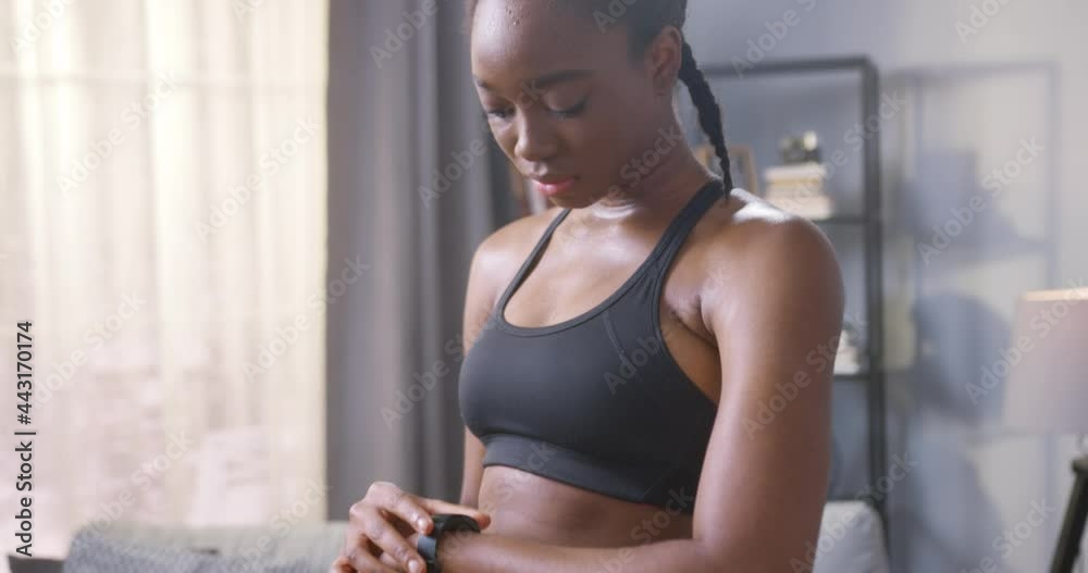 Close-up of multiracial brunette woman checking pulse on her watch while training at her cozy flat. Sports, strength and endurance concept Close-up of multiracial brunette woman checking pulse on her watch while training at her cozy flat. Sports, strength and endurance concept
