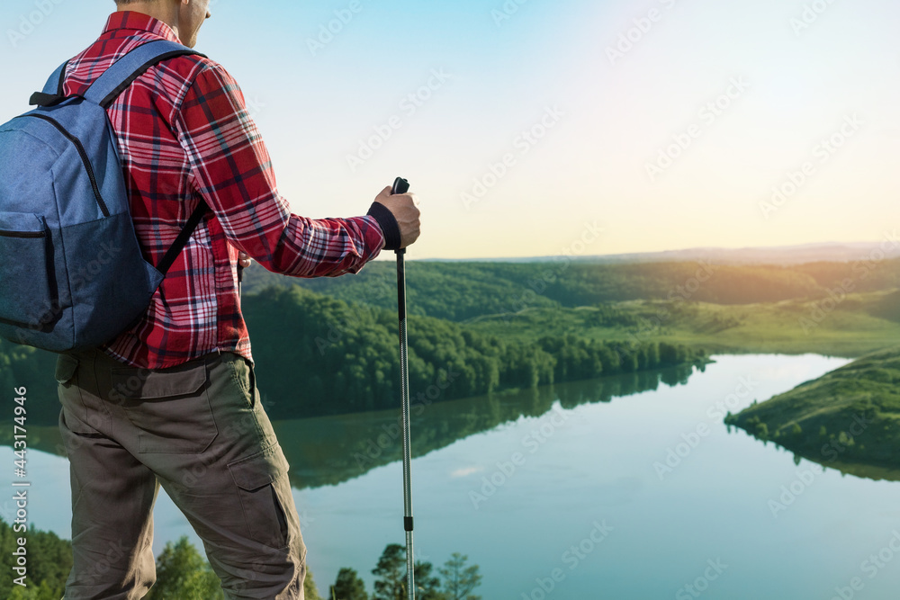 Man in contemplation, sunset, nature. Man standing on a top of mountain, enjoying the beautiful sunset over a wide river valley.