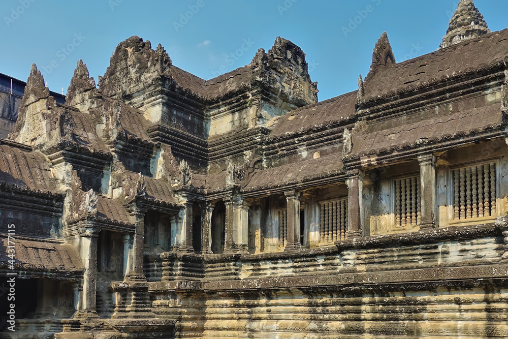 Obraz premium Details of the architecture of the temple in the ancient city of Angkor. Weathered stone steps, columns, galleries are visible. High carved towers against the blue sky. Cambodia.