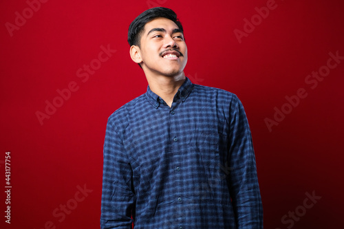 Young handsome man wearing casual shirt over looking away to side with smile on face, natural expression. © Reza