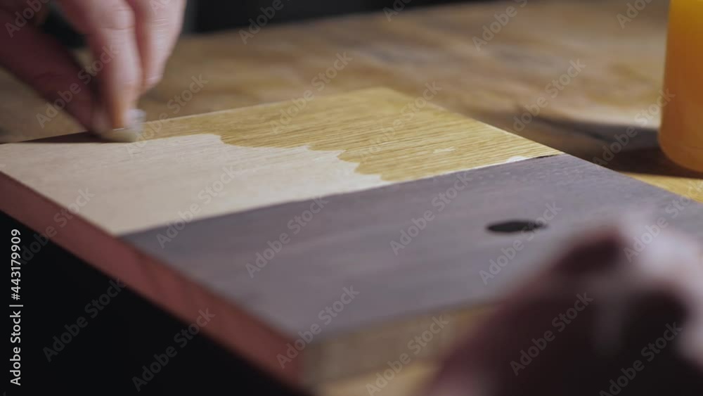 applying oil on a wooden oak board with a sponge. application of wood impregnation. woodworking concept. wood stain applying oil on a wooden oak board with a sponge. application of wood impregnation. woodworking concept. wood stain