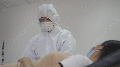 man in ppe suit holding clipboard checking patient