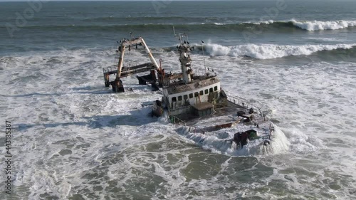 Aerial orbiting shot showing waves crashing on the Zeila Shipwreck near Henties Bay, Skeleton Coast, Namibia. photo