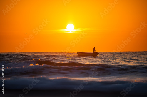 Fisherman sailing with his boat on beautiful sunrise over the sea © Gerisima
