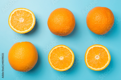 Top view photo of six oranges three whole and three halves in two rows on isolated pastel blue background