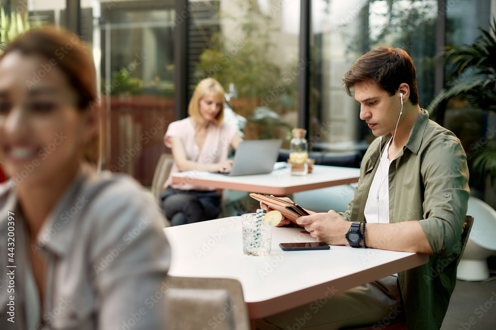 Male entrepreneur with reading an e-mail on digital tablet in a cafe. Male entrepreneur with reading an e-mail on digital tablet in a cafe.