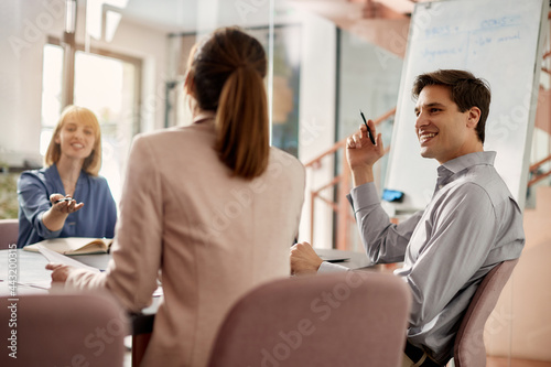 Happy male entrepreneur having business meeting with female coworkers in the office.