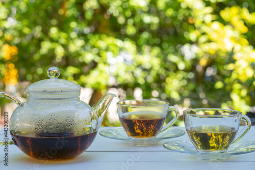 teapot and cups of green and chinese tea on white table in garden