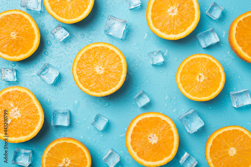 Top view photo of orange slices ice cubes and water drops on isolated light blue background