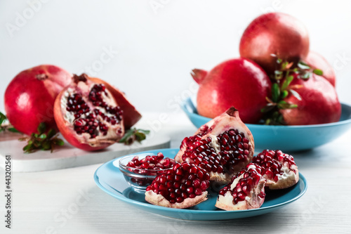 Delicious ripe pomegranates on white wooden table