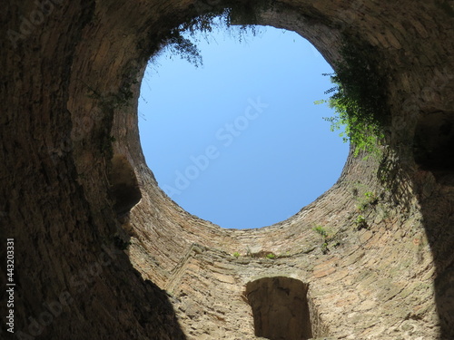 round window to the blue sky from a stone tower, the tower is overgrown with grass