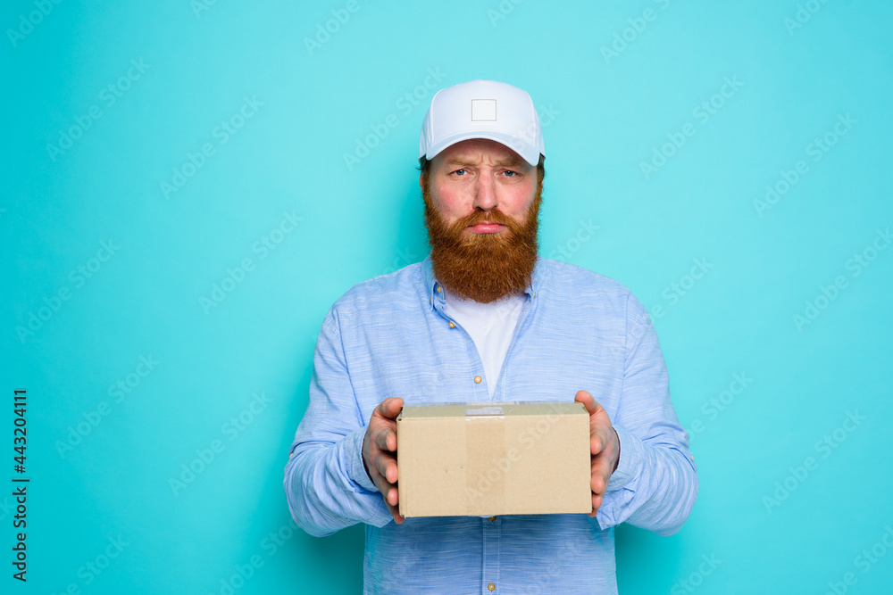 Courier with hat is unhappy to deliver a carton box Courier with hat is unhappy to deliver a carton box