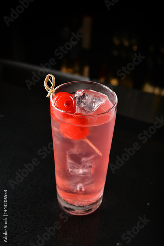 bartender special cold pink fruit punch cocktail wine or mocktail with cherry pop juice in tall glass goblet on black background luxury hotel pub iced beverage menu photo