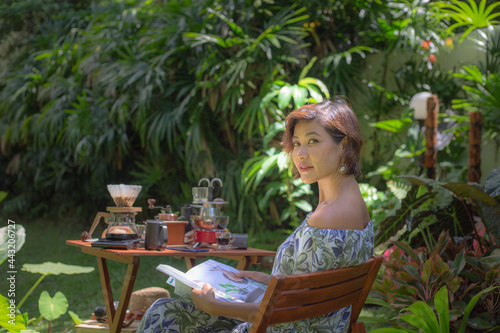 ThailandA woman drink hot coffee in green garden. .A woman relax in green garden with coffee set on wooden table. .green garden background. photo
