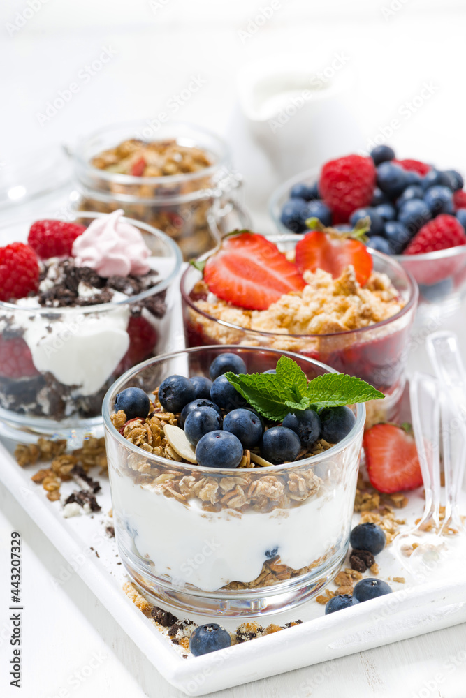 sweet desserts with fresh berries in glasses on white wooden tray, top view closeup sweet desserts with fresh berries in glasses on white wooden tray, top view closeup