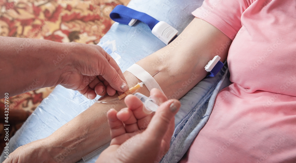 Doctor inputs liquid medicine by syringe to catheter in vein. Doctor inputs liquid medicine by syringe to catheter in vein.