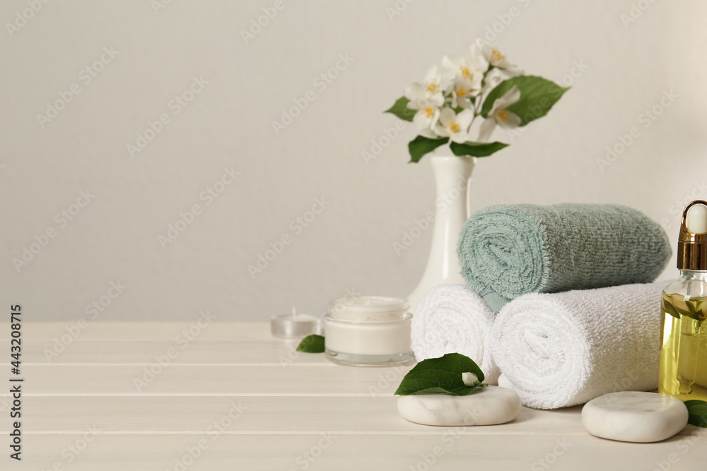 Composition with spa stones and beautiful jasmine flowers on white wooden table, space for text