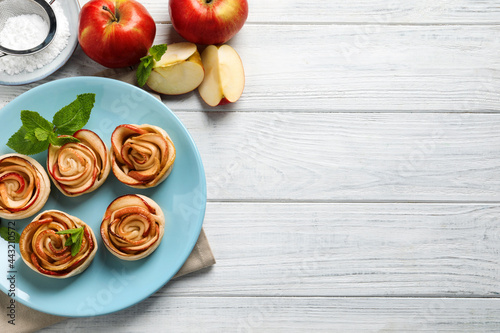 Freshly baked apple roses on white wooden table, flat lay. Space for text