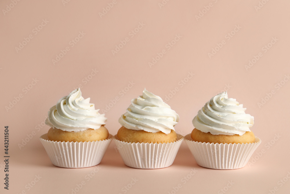 Delicious cupcakes with white cream on pink background