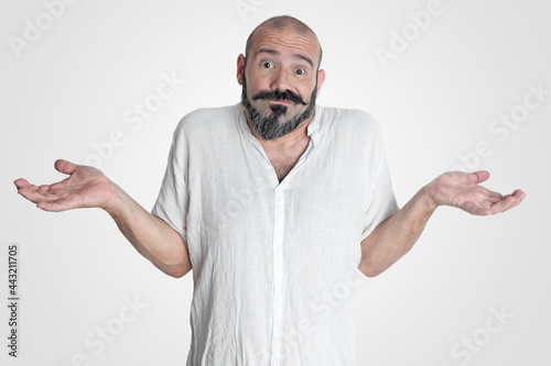 Caucasian man with mustache and beard making an expression of I don't know, dressed in white on white background