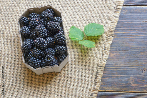 Blackberries from market.  Fresh ripe blackberries in cardboard box on rustic table. Flat lay. Free space for text