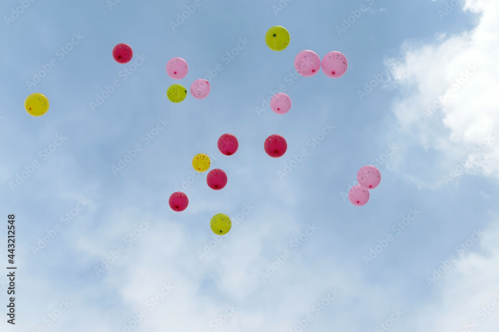 Many colorful balloons are flying in the sky against the background of clouds