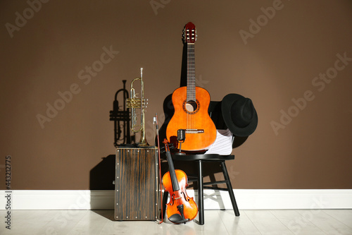 Set of different musical instruments near brown wall indoors