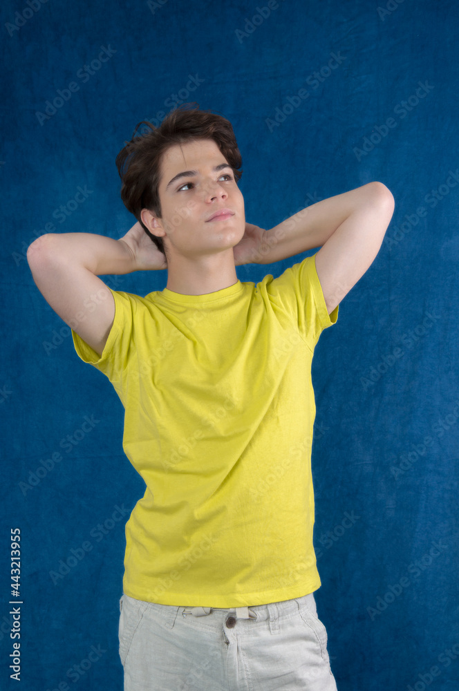 Young guy looking up right in yellow shirt, brown hair isolated on blue background