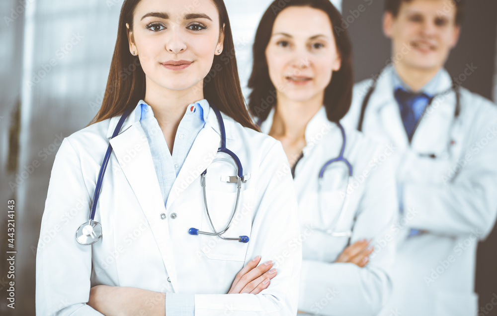 Group of young professional doctors is standing as a team with arms crossed in a hospital office and is ready to help patients. Medical help, insurance in health care, best disease treatment and