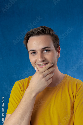 young caucasian man with long false nails looking you and smiling on blue background