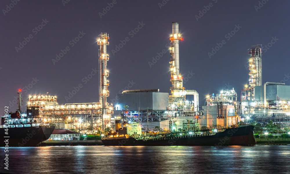The landscape view oil and gas tank with oil refinery background at night with soft blurred focus. Intend to use for industry and industrial background element.