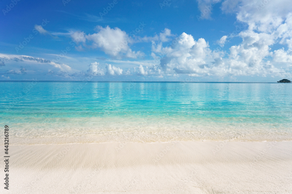 Beautiful sandy beach with white sand and rolling calm wave of turquoise ocean on Sunny day. White clouds in blue sky are reflected in water. Perfect tropical seascape, copy space. Beautiful sandy beach with white sand and rolling calm wave of turquoise ocean on Sunny day. White clouds in blue sky are reflected in water. Perfect tropical seascape, copy space.