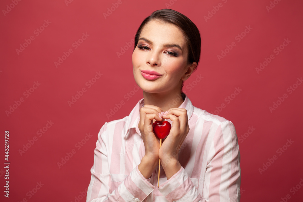 Beautiful young woman hugging in the shape of a heart red heart and smiling on red background. Beautiful young woman hugging in the shape of a heart red heart and smiling on red background.