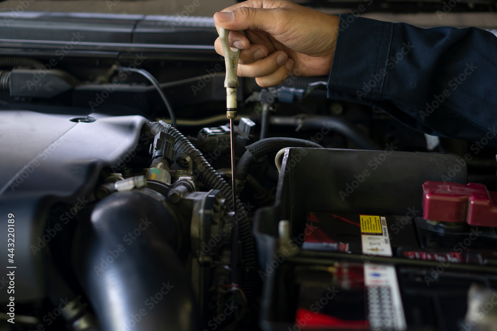 Mechanic's hand reaches the point of checking the engine oil level from the engine. Mechanic's hand reaches the point of checking the engine oil level from the engine.
