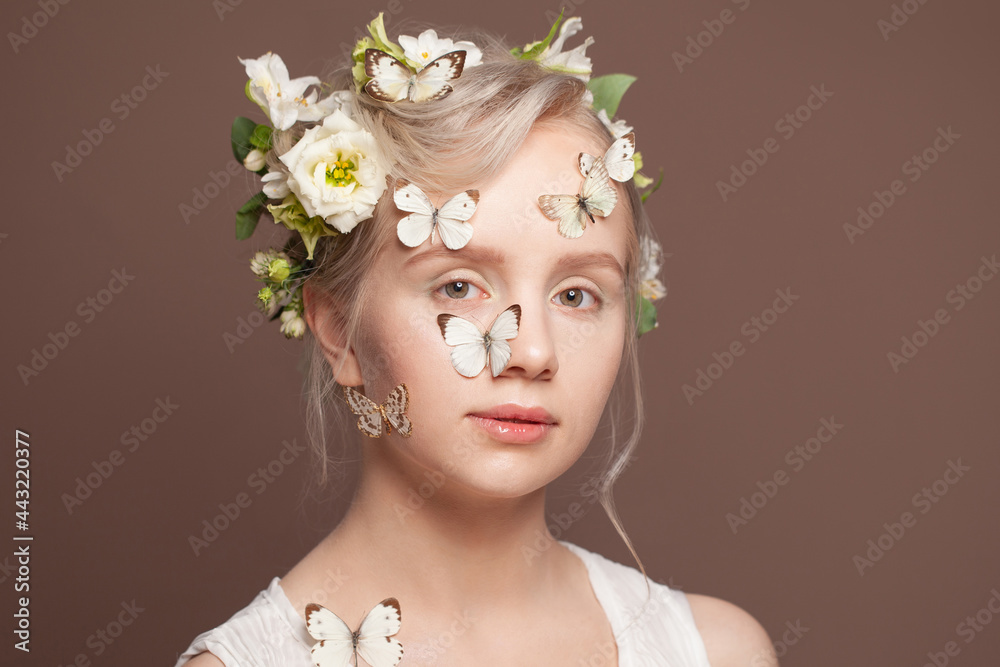 Beauty fantasy model spring woman with white flowers and butterfly on her head and skin. Art design portrait of beautiful summer young woman