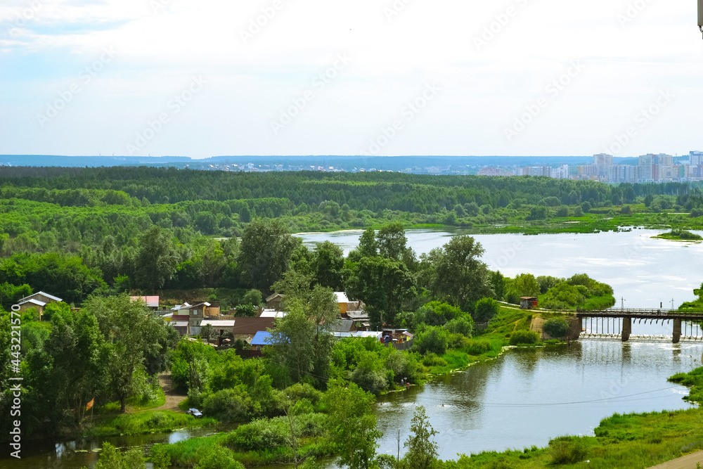 Settlement on the banks of a river along a dense, bright green forest Settlement on the banks of a river along a dense, bright green forest