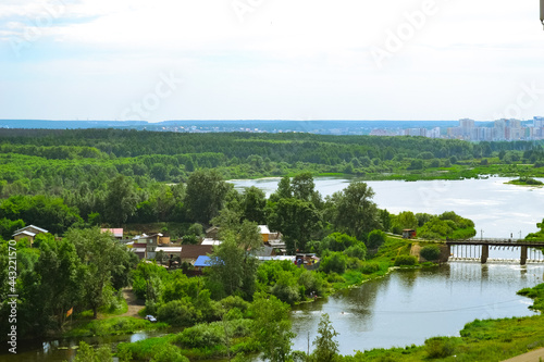 Settlement on the banks of a river along a dense  bright green forest