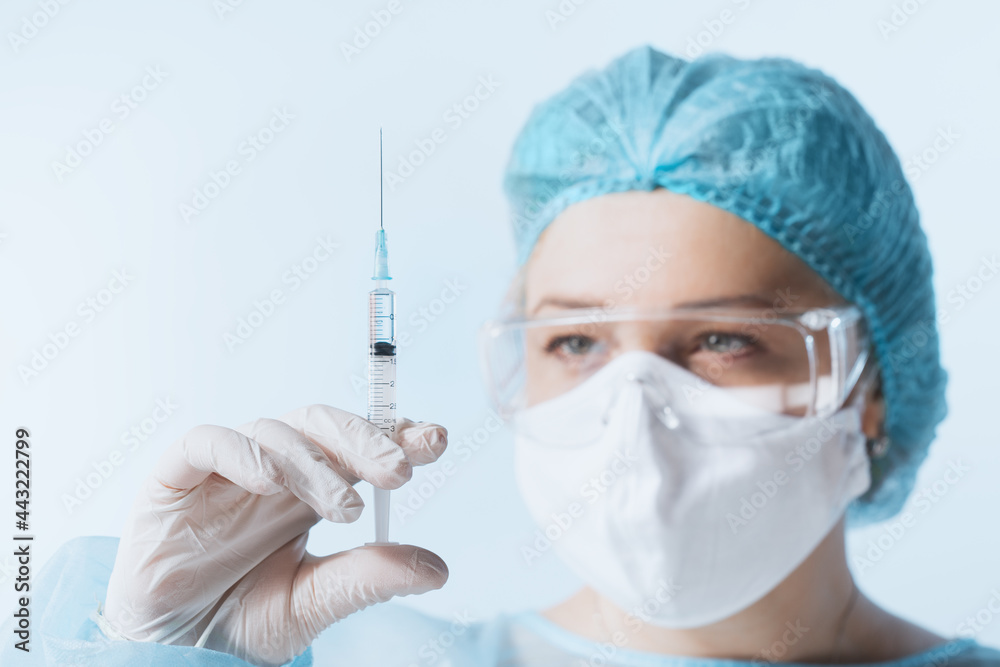 Close up view of doctor with the syringe of covid vaccine on blue back Close up view of doctor with the syringe of covid vaccine on blue back
