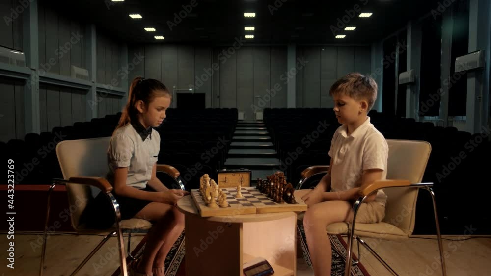 Pupils boy and girl play chess in the assembly hall Pupils boy and girl play chess in the assembly hall