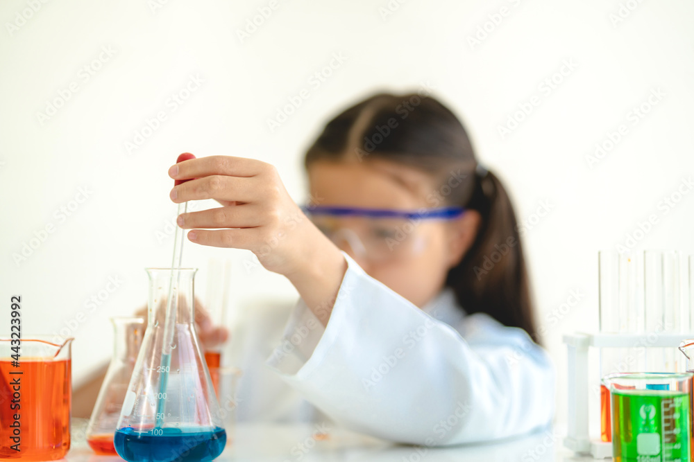 Cute little girl student child learning research and doing a chemical experiment while making analyzing and mixing liquid in glass at science class in school.Education and science concept Cute little girl student child learning research and doing a chemical experiment while making analyzing and mixing liquid in glass at science class in school.Education and science concept