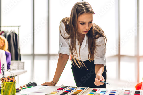 Portrait of young beautiful pretty woman fashion designer stylish sitting and working.Attractive young girl use desktop conputer and colorful fabrics at fashion design studio photo