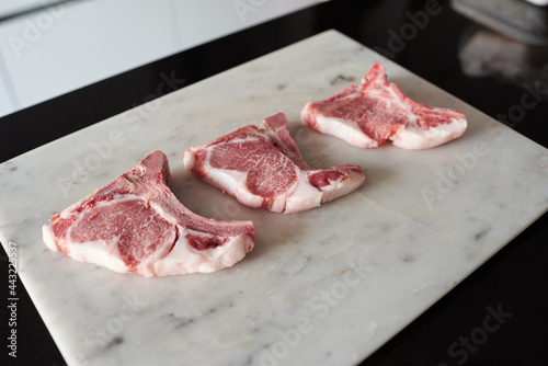 Raw Iberian pork chops on a white marble table